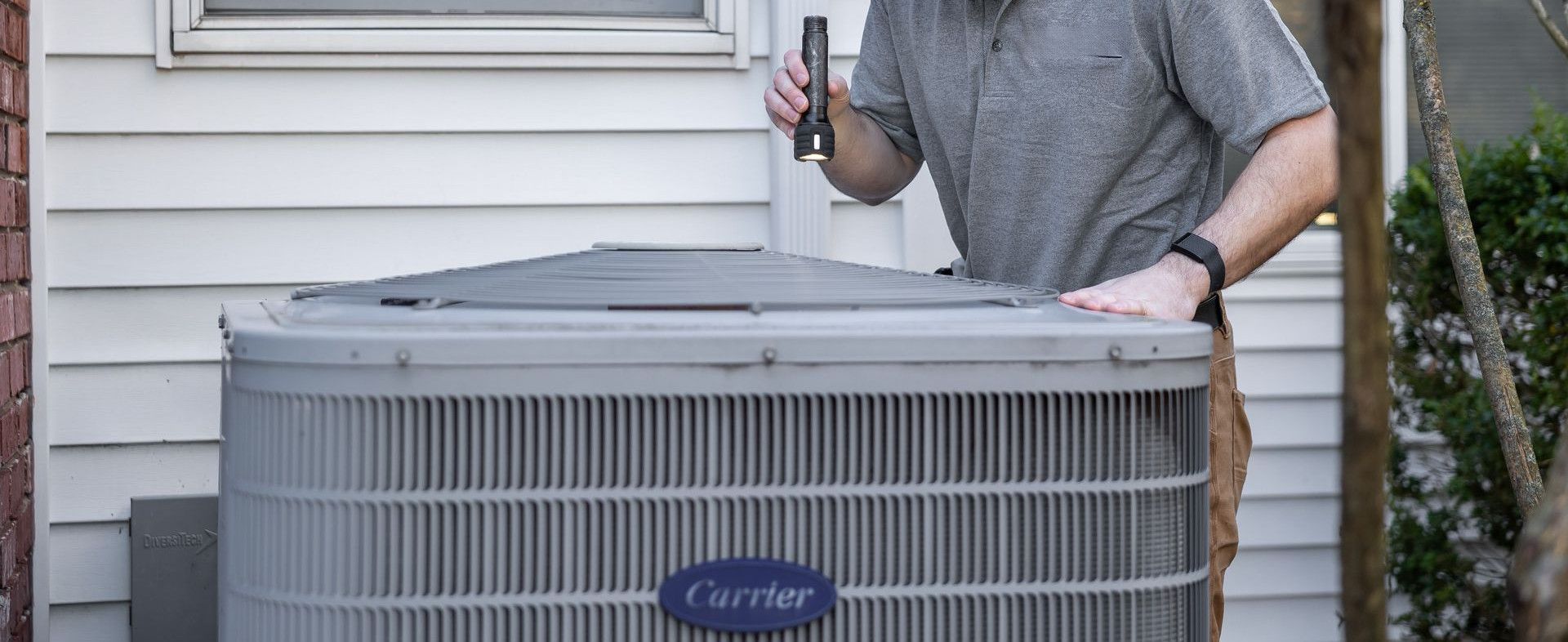 A technician inspects an outdoor HVAC unit for maintenance.